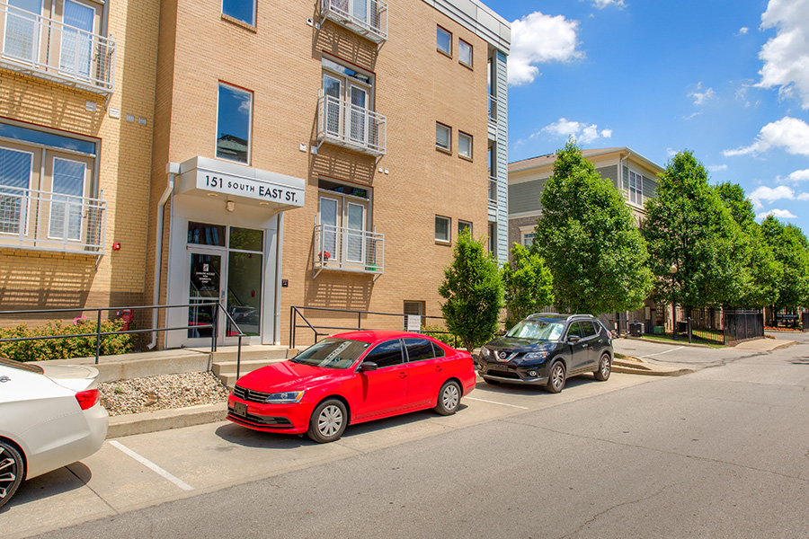 Several cars parked in front of the entrance located at Waverly Apartments.